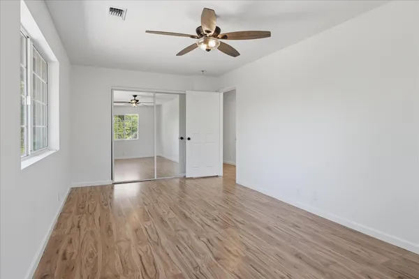 a view of empty room with wooden floor and fan