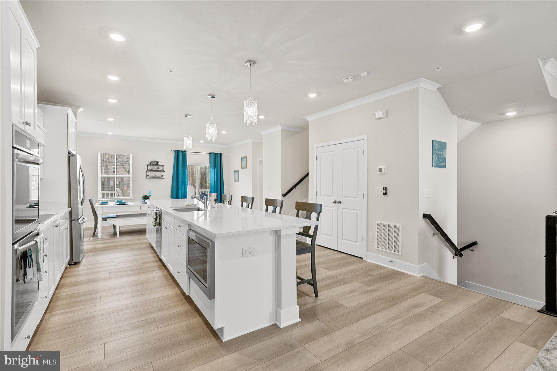 9503 Seascape Lane, Unit 4 Berlin, MD 21811 - Photo 22 of 52 a large white dining hall with stainless steel appliances granite countertop a stove oven a refrigerator with white cabinets and wooden floor