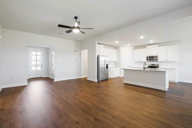a kitchen with granite countertop white cabinets and a wooden floor