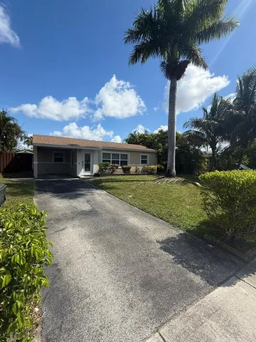 a front view of a house with a yard and palm trees
