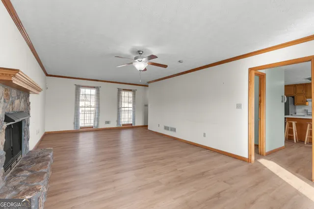 an empty room with chandelier fan and fireplace