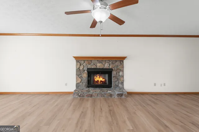 a view of an empty room with wooden floor and a fireplace