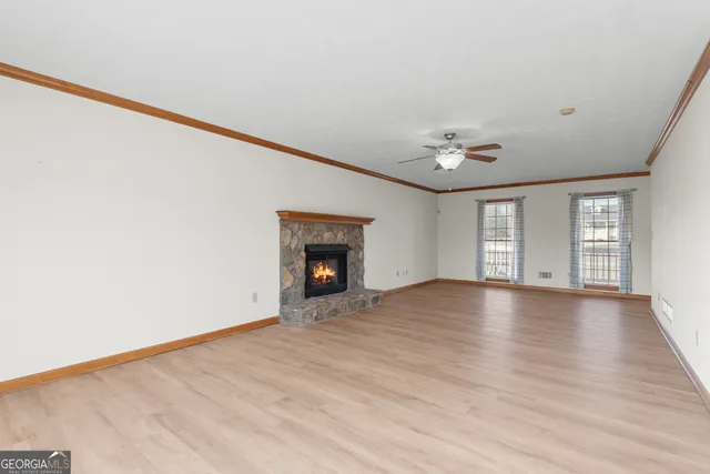 a view of an empty room with a window and wooden floor