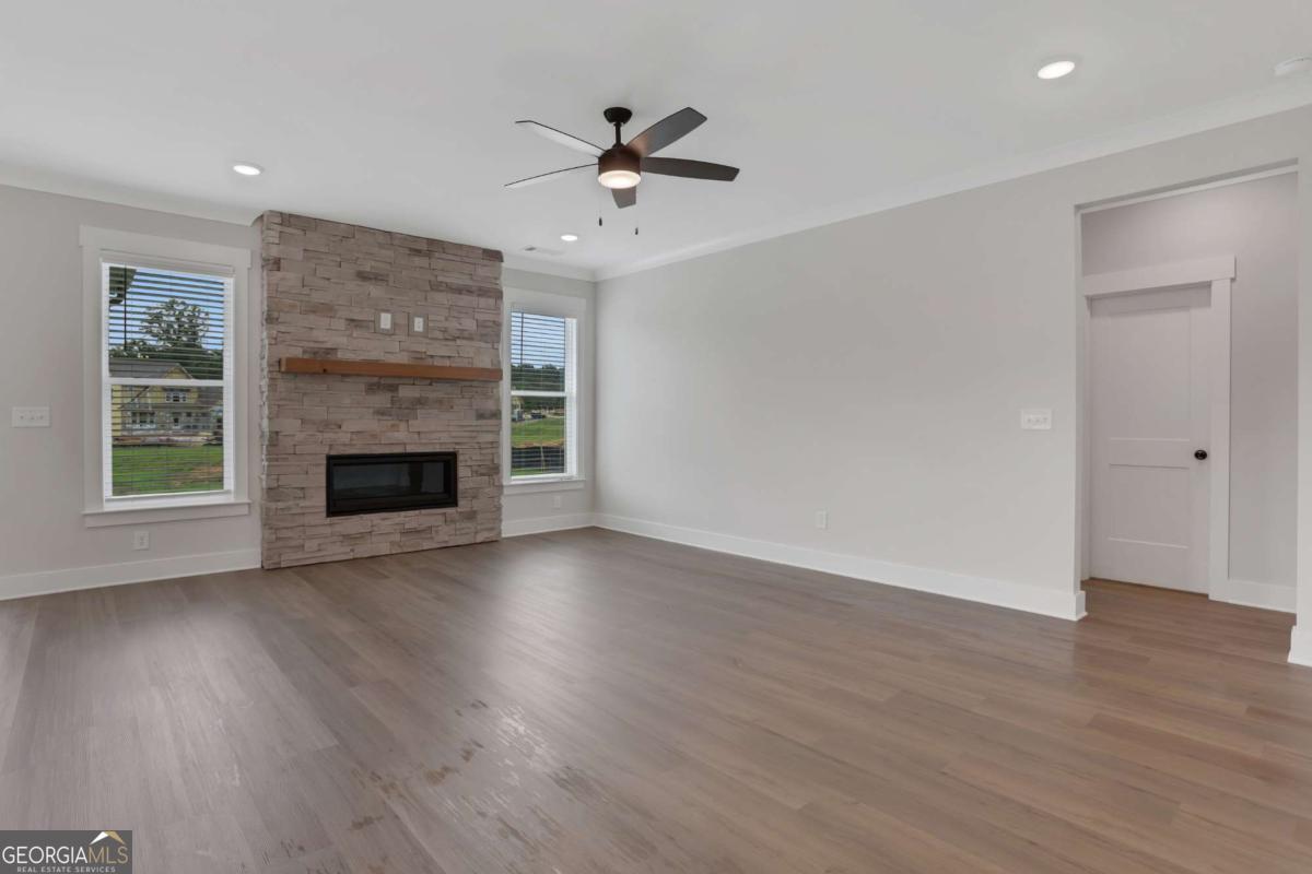 4230 Mary Ruth Way Loganville, GA 30052 - Photo 12 of 51 an empty room with wooden floor a ceiling fan a fireplace and windows