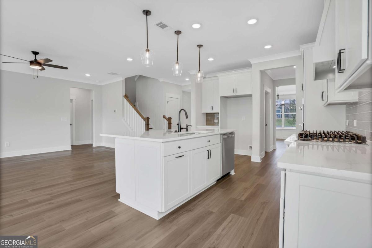 4230 Mary Ruth Way Loganville, GA 30052 - Photo 13 of 51 a large white kitchen with kitchen island a stove a sink dishwasher and a fireplace with wooden floor