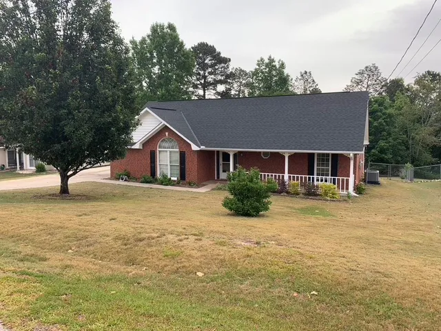 a front view of house with yard and trees in the background