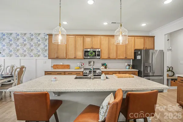 a kitchen with stainless steel appliances granite countertop a dining table chairs refrigerator and sink