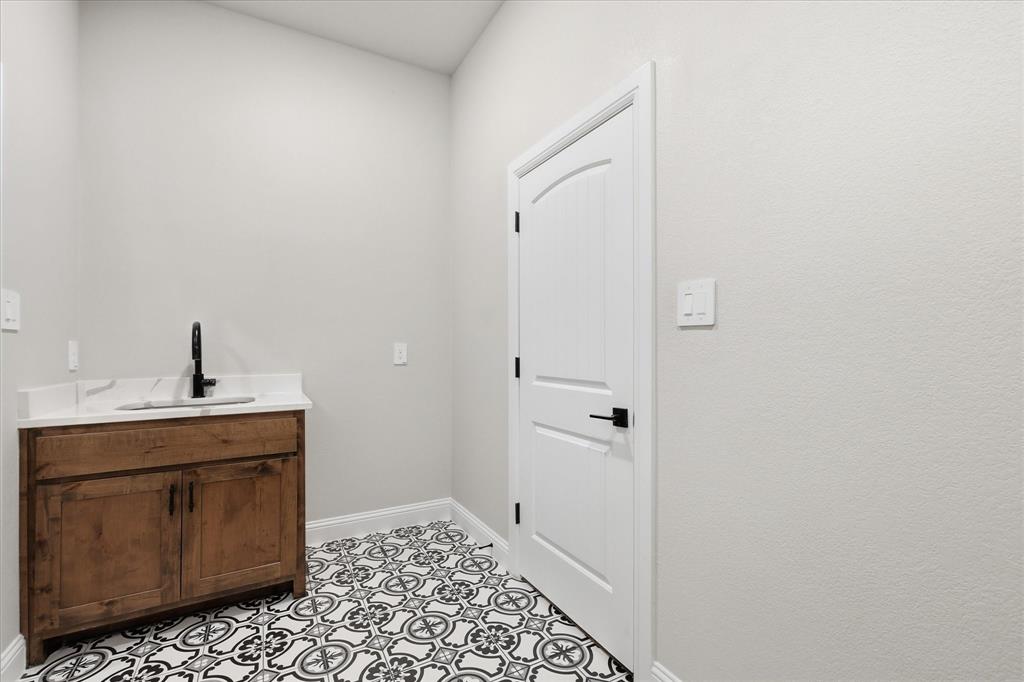 120 Grace Vw Road Weatherford, TX 76088 - Photo 21 of 40 Powder room featuring a custom wood vanity with a white countertop and rectangular sink, matte black faucet, and patterned floor tile