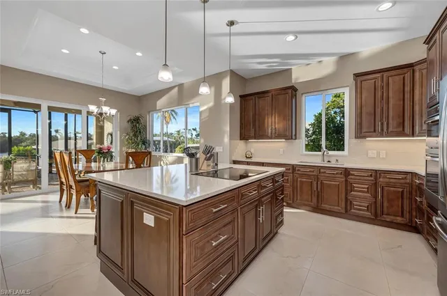 a kitchen with kitchen island granite countertop a sink stove and a refrigerator with wooden cabinets