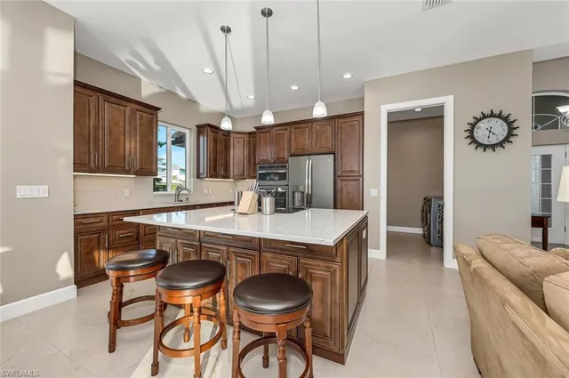 a kitchen with kitchen island granite countertop a sink and a refrigerator