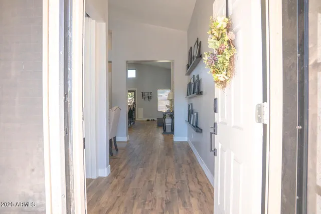 a view of a hallway with wooden floor and a bathroom