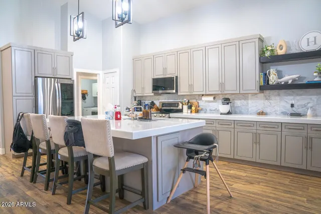a kitchen with stainless steel appliances kitchen island granite countertop a table chairs sink and cabinets