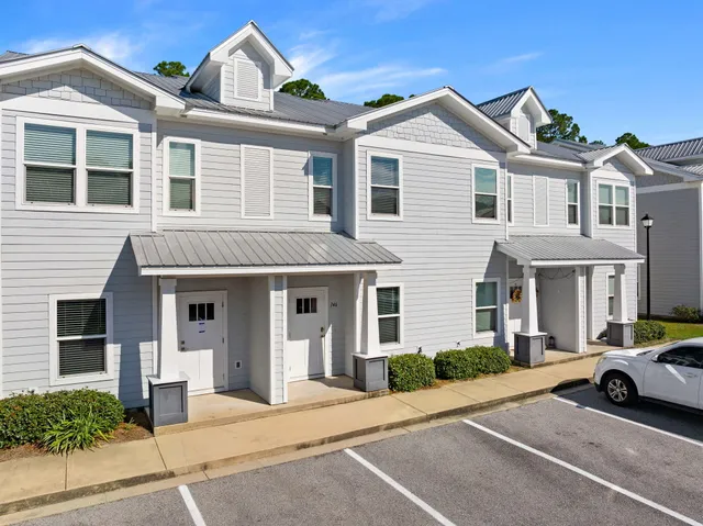 a view of a white house with large windows and a table and chairs