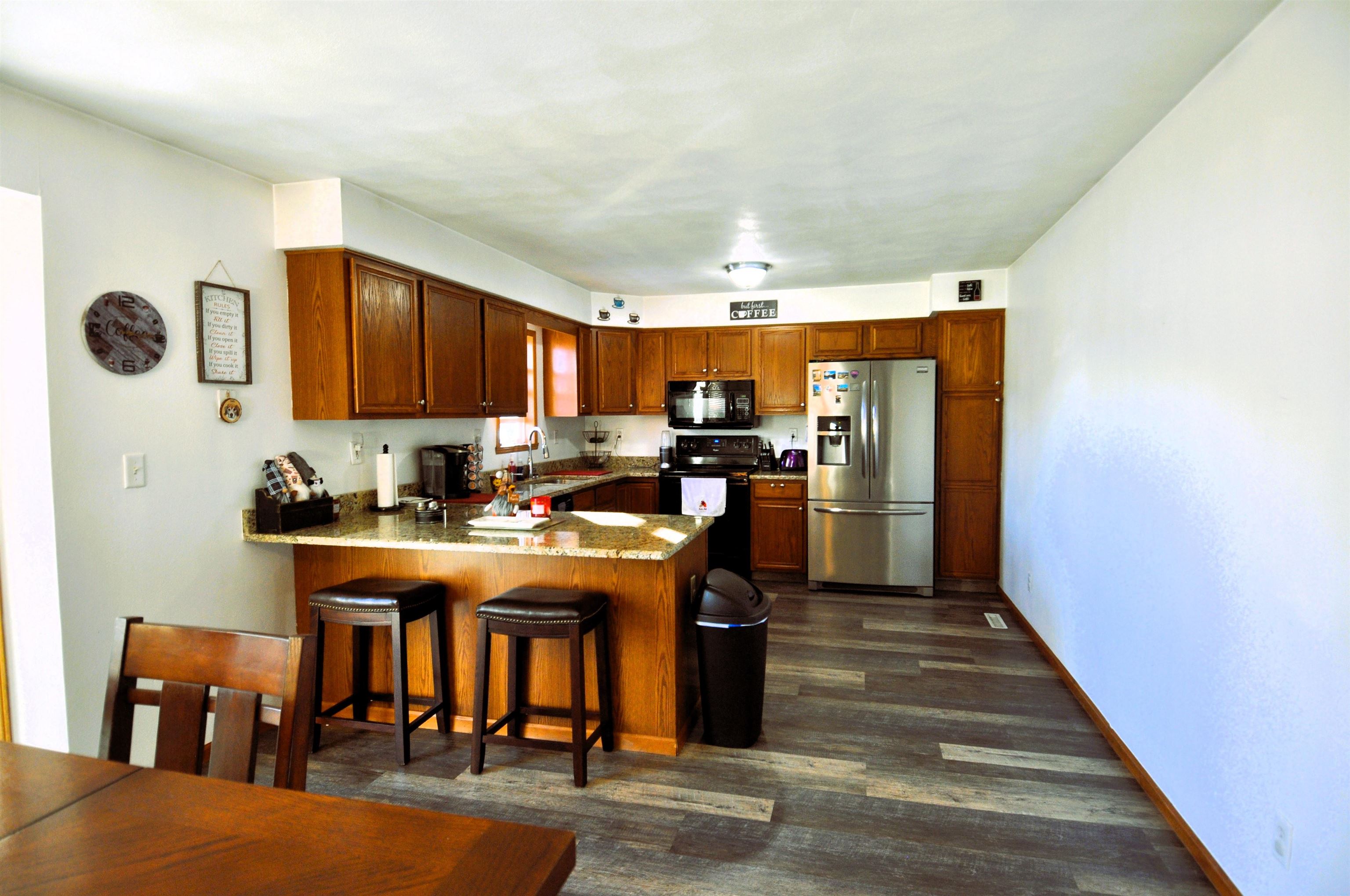 518 Merilot Drive Roscoe, IL 61073 - Photo 9 of 26 a kitchen with stainless steel appliances granite countertop a stove a refrigerator a sink a dining table and chairs with wooden floor