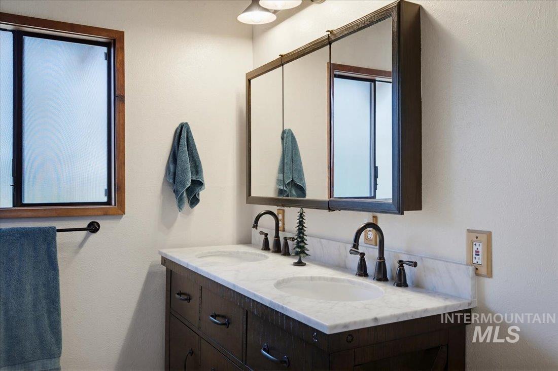 143 East Lk Frk Road McCall, ID 83638 - Photo 20 of 49 Double vanity featuring integrated sinks, a marble-finish countertop, and dark-finish cabinetry
