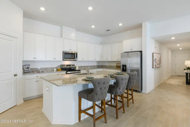 a kitchen with stainless steel appliances a stove a sink a microwave a dining table and chairs