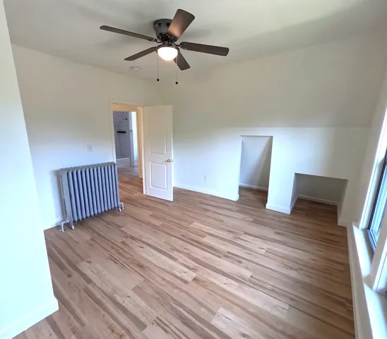 a view of a bedroom with wooden floor and ceiling fan
