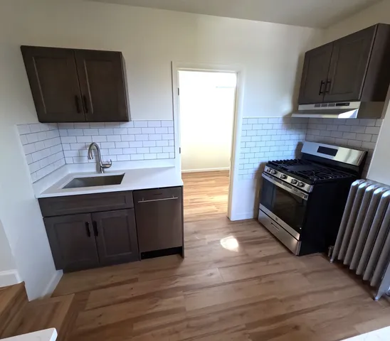 a kitchen with granite countertop wooden cabinets and a stove top oven