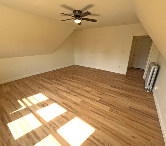 a view of a room with wooden floor and a ceiling fan