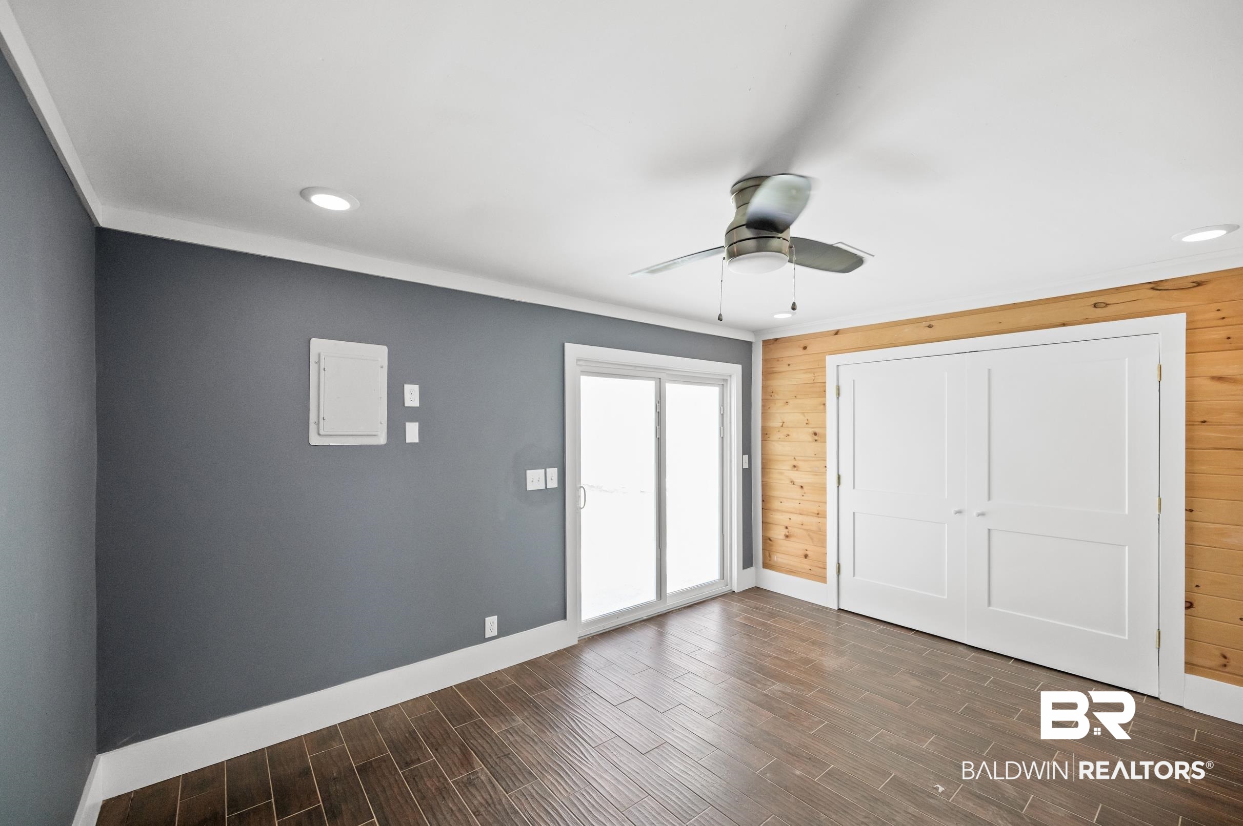 24663 Chestnut Street Elberta, AL 36530 - Photo 13 of 22 Room featuring wood-finish tile flooring, a dark gray accent wall, and a natural wood-paneled wall