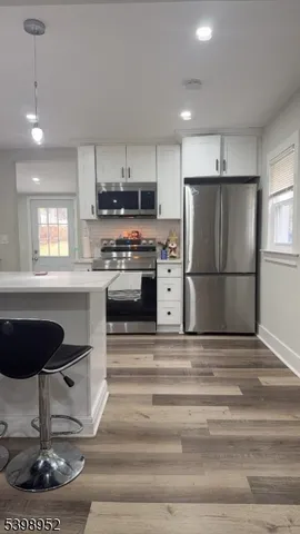 a kitchen with stainless steel appliances granite countertop a refrigerator a stove a sink dishwasher a dining table and chairs with wooden floor