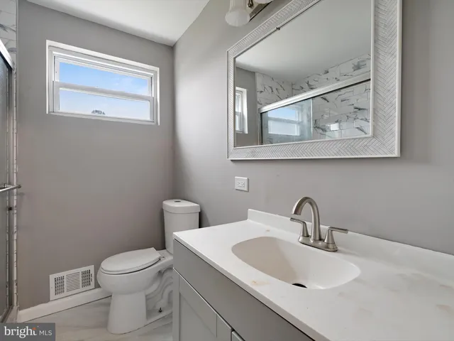 a bathroom with a toilet a sink and mirror