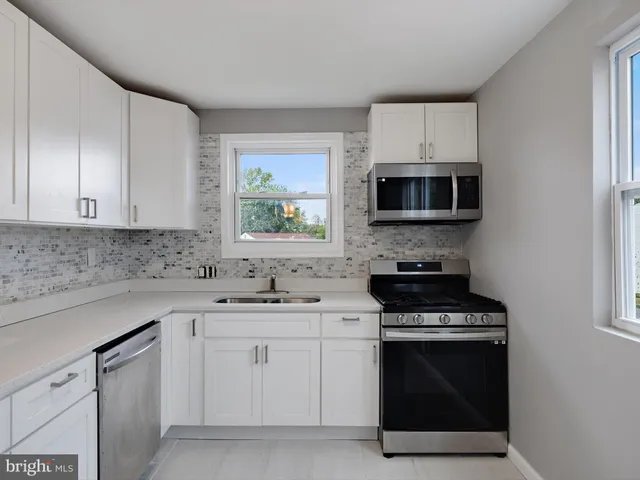 a kitchen with white cabinets and appliances