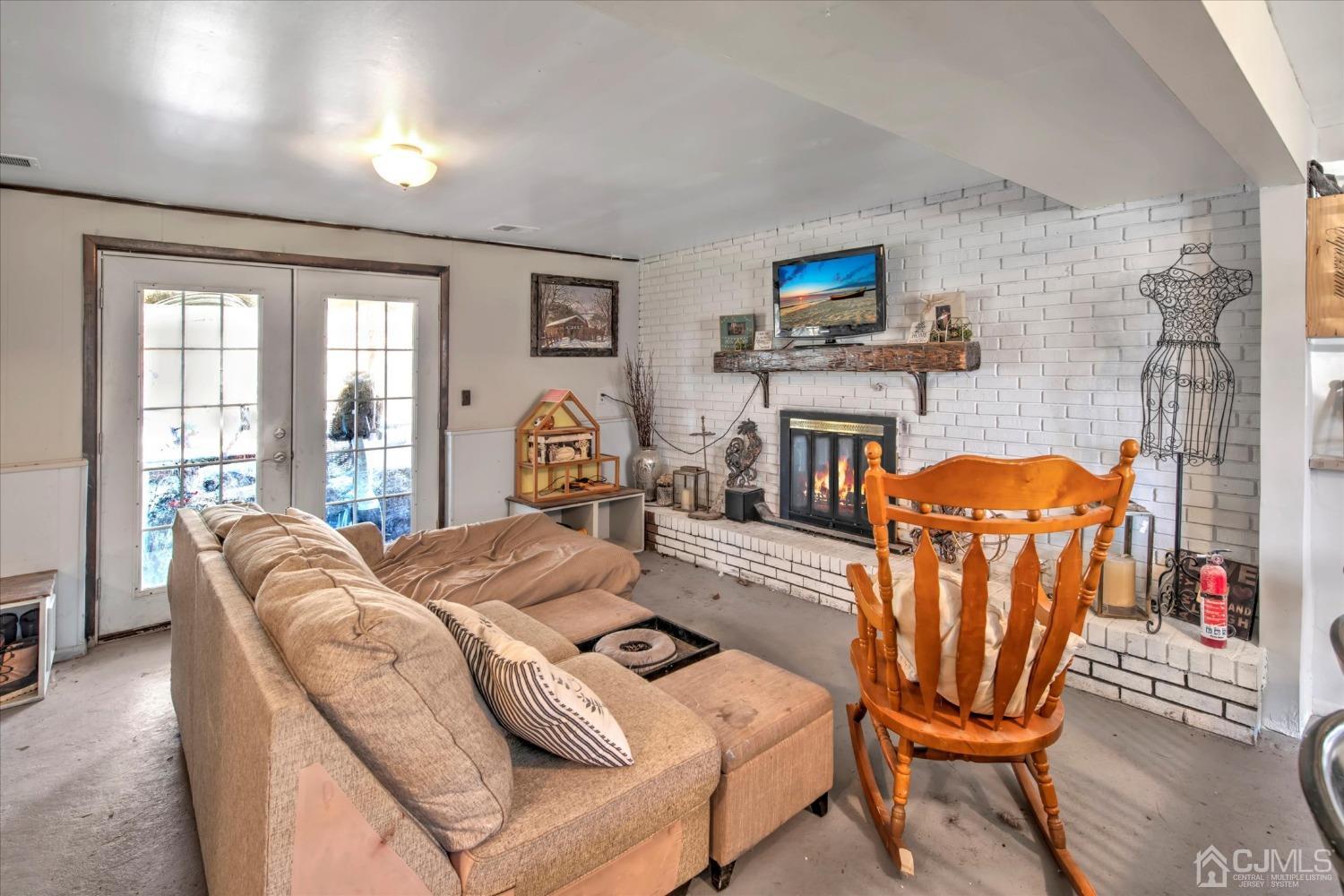59 Sunnyside Road Howell, NJ 07731 - Photo 16 of 26 a living room with furniture a flat screen tv and floor to ceiling windows