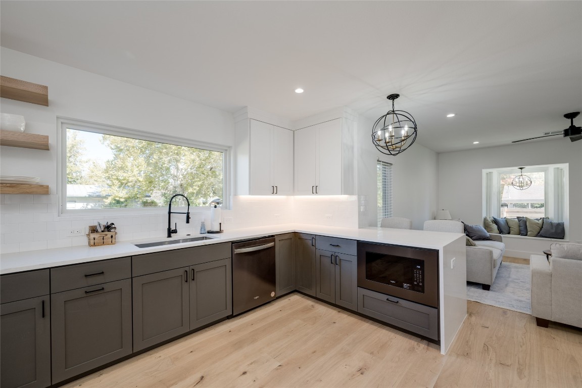 a large white kitchen with a sink and dishwasher next to a large window