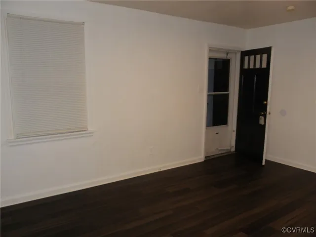 a view of an empty room with wooden floor and closet