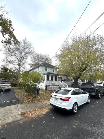 a front view of a house with cars parked on road