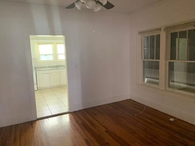 an empty room with wooden floor cabinet and windows