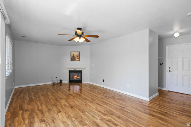 142 East 2675th Street South Clearfield, UT 84015 - Photo 15 of 49 Living space featuring wood-finish flooring, a corner fireplace with a white mantel, and a ceiling fan