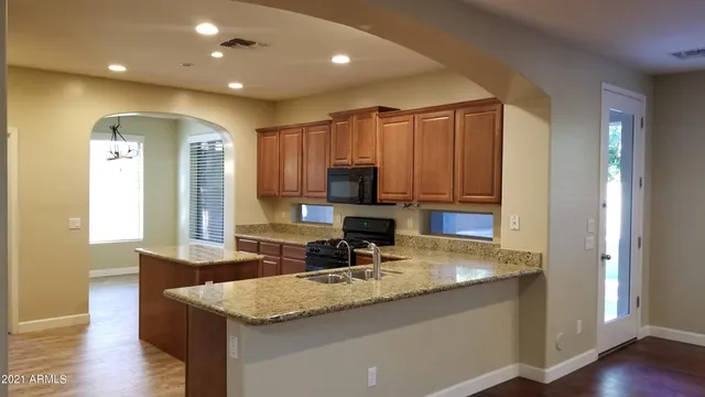 a kitchen with kitchen island granite countertop a sink and refrigerator