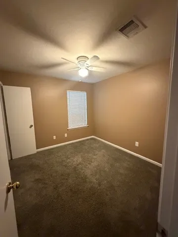 an empty room with windows and fan