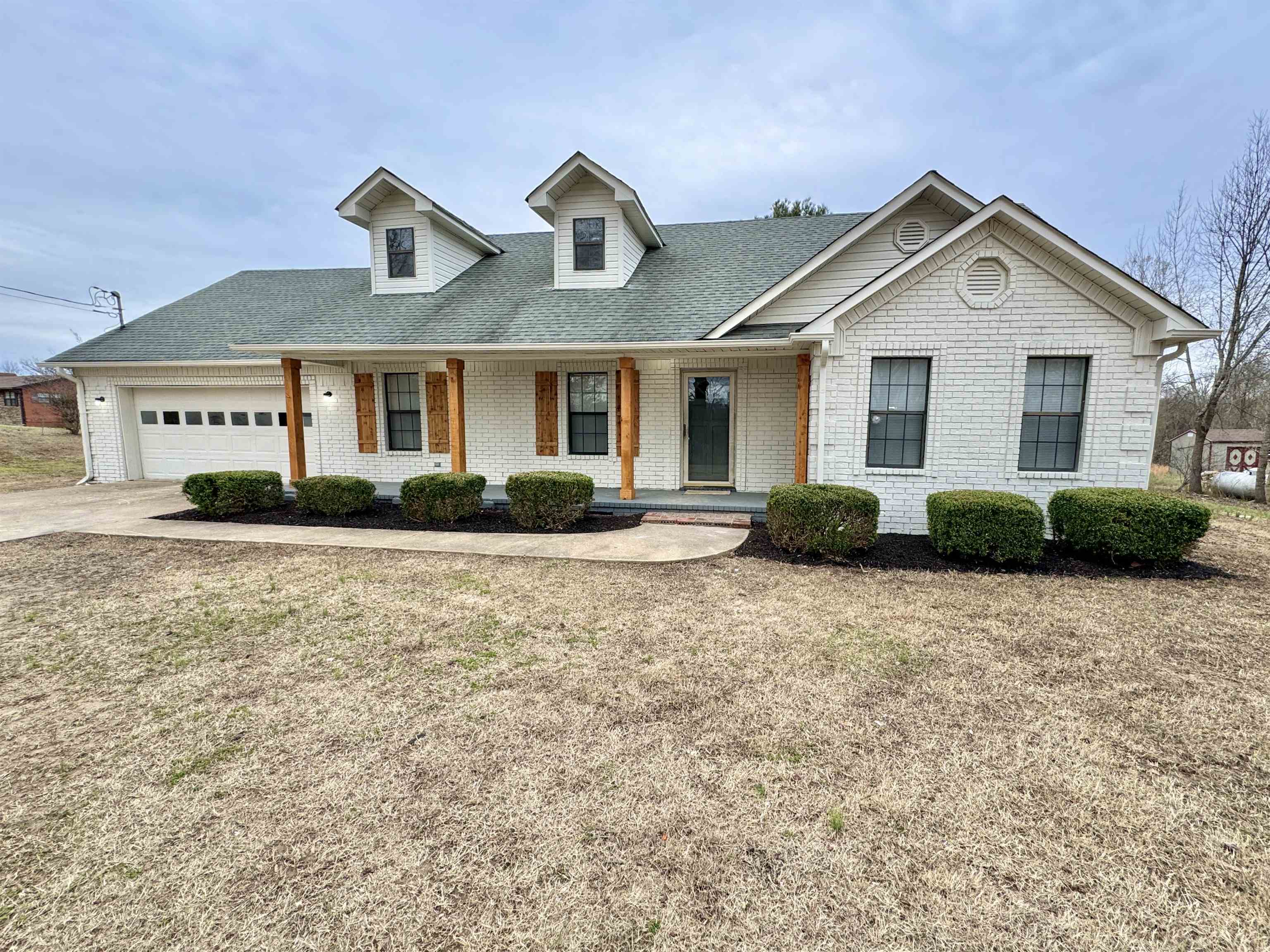 View of front of house with a garage, covered porch, and a front lawn