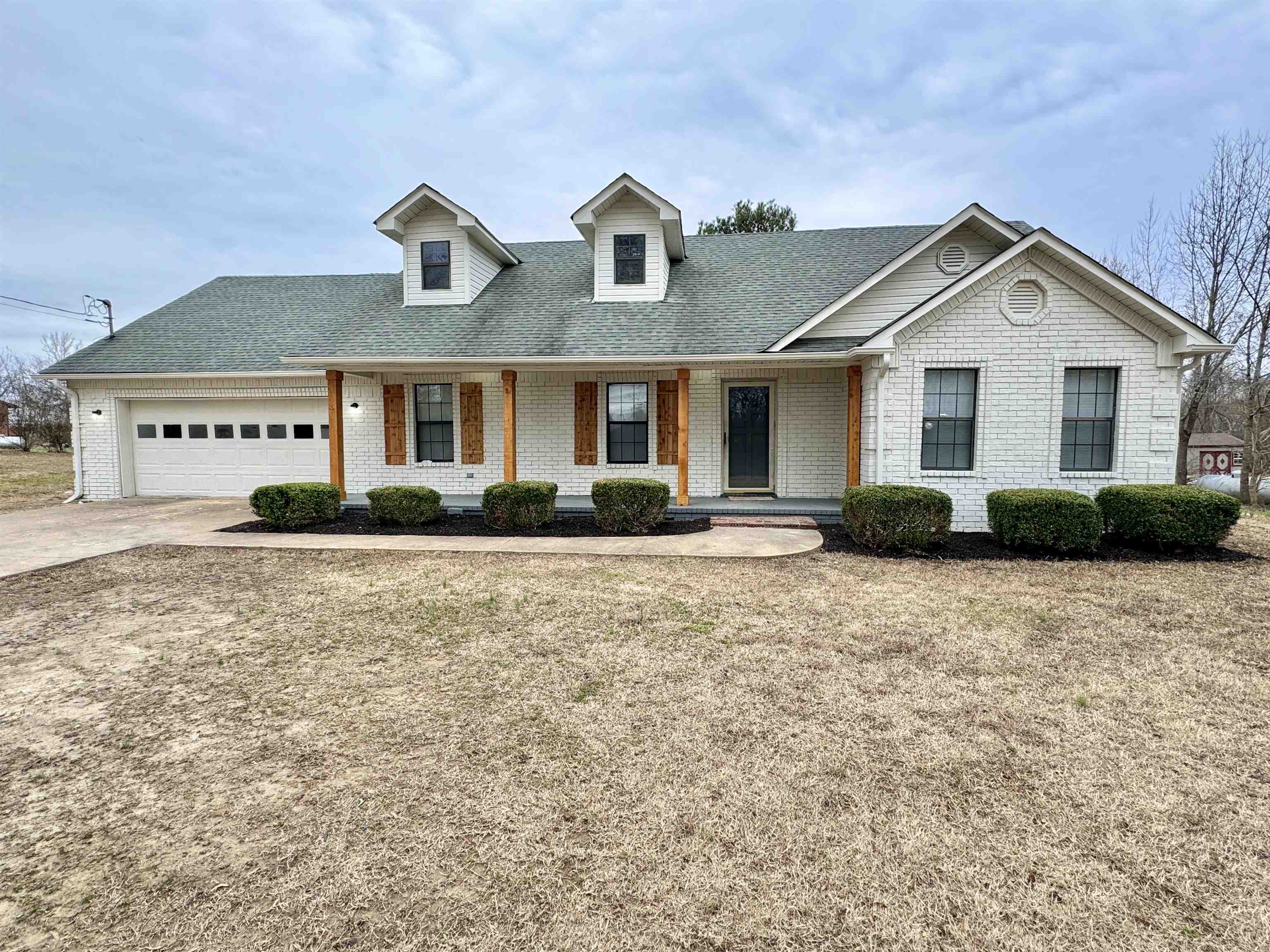 View of front of house featuring a porch, a garage, and a front lawn
