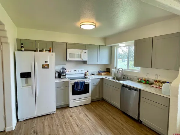 a kitchen with kitchen island wooden floors appliances and cabinets