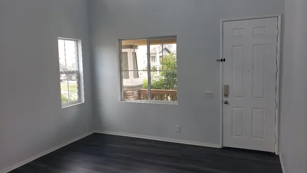 a view of an empty room with wooden floor and a window