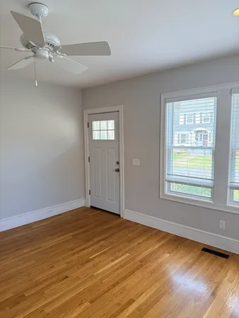 a view of an empty room with wooden floor and a window