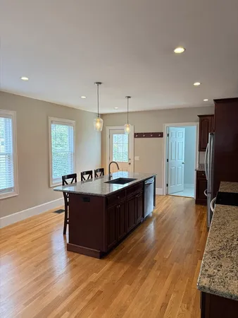 a living room with couches and kitchen view with wooden floor