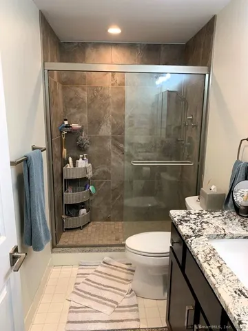 a bathroom with a granite countertop sink a toilet a mirror and shower