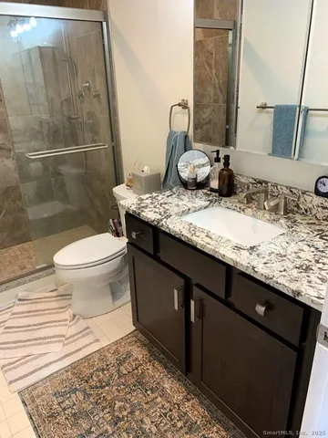 a bathroom with a granite countertop sink toilet and a mirror