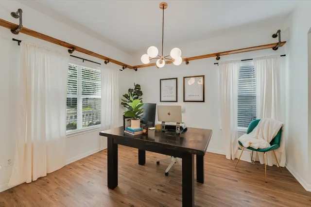 a dining room with wooden floor a chandelier a wooden table and chairs