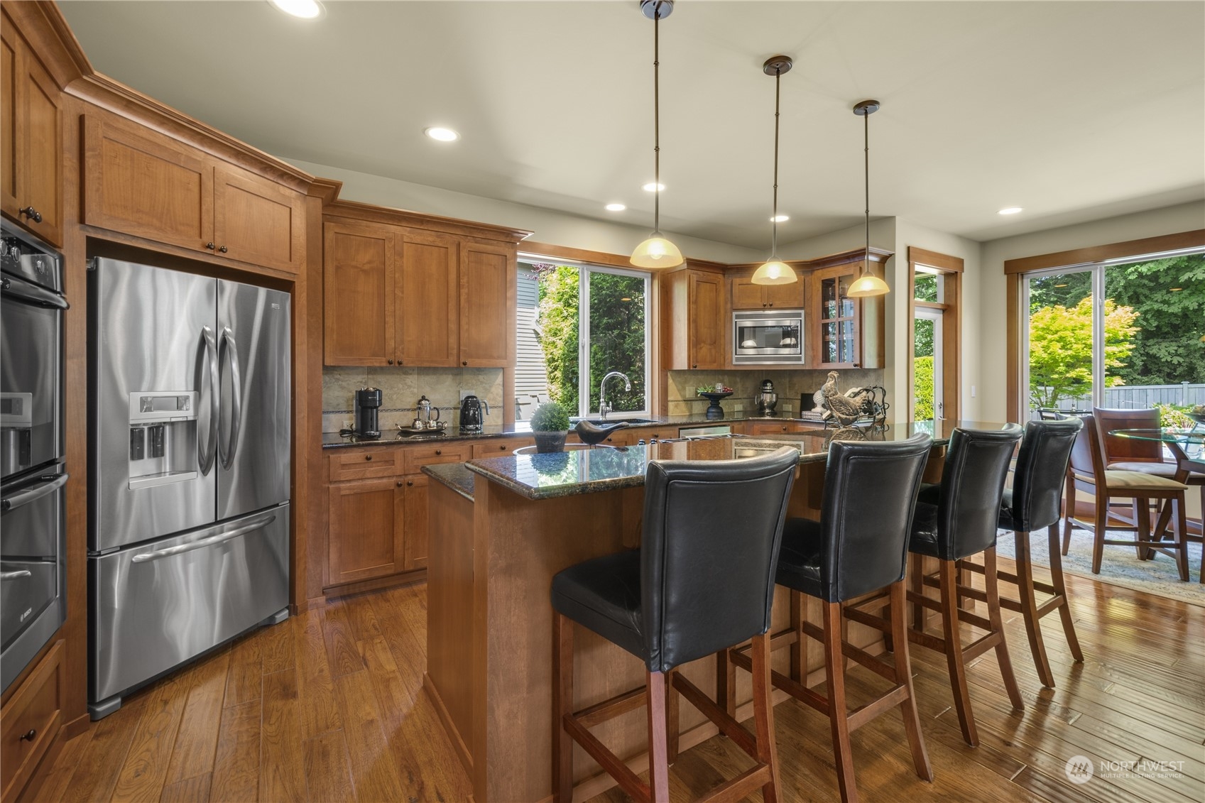 4205 221st Place Southeast Bothell, WA 98021 - Photo 13 of 32 a kitchen with stainless steel appliances granite countertop a refrigerator a stove a sink a dining table and chairs with wooden floor