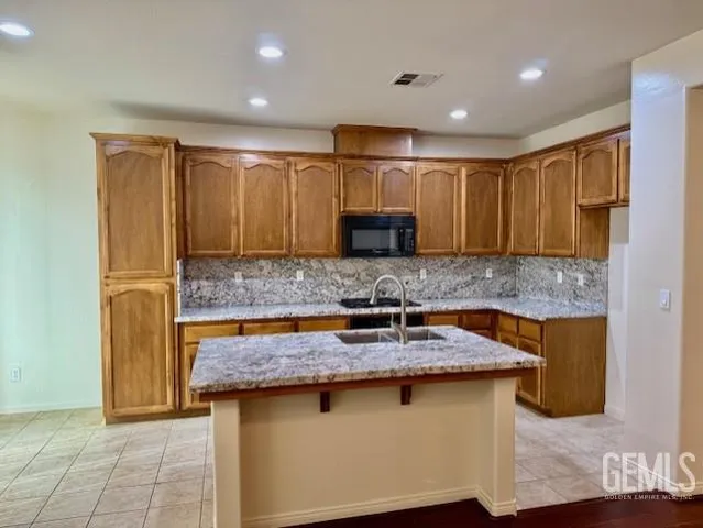 a kitchen with kitchen island granite countertop a sink and a stove