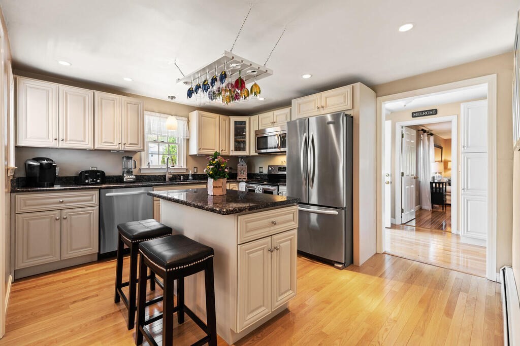 81 Baxter Street Melrose, MA 02176 - Photo 11 of 33 a kitchen with stainless steel appliances granite countertop a refrigerator a sink dishwasher a stove and white cabinets with wooden floor