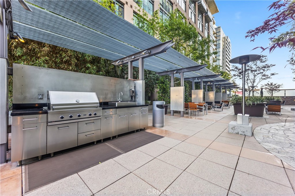 1100 South Hope Street, Unit 1704 Los Angeles, CA 90015 - Photo 24 of 26 a kitchen with stainless steel appliances kitchen island granite countertop a table and chairs in it