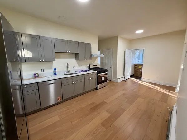 a kitchen with stainless steel appliances a sink a stove a refrigerator cabinets and a window