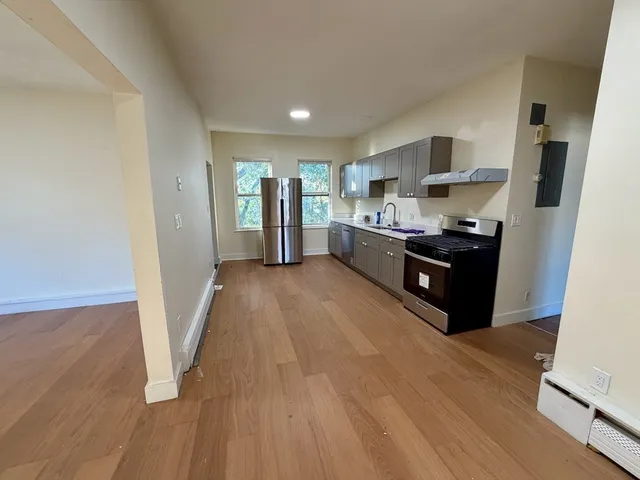 a living room with stainless steel appliances furniture a refrigerator and a view of kitchen